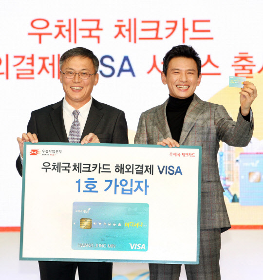 우정사업본부가 5일 인천국제공항에서 전 세계 VISA 가맹점에서 우체국체크카드를 사용할 수 있는 '우체국 체크카드 해외결제서비스' 출시 기념식을 열었다.       강성주 우정사업본부장(왼쪽)과 우체국 해외체크카드 1호 가입자인 우체국 금융모델 탤런트 황정민이 기념촬영을 하고 있다.